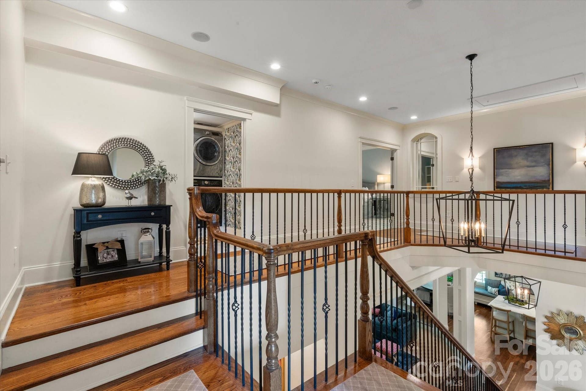Wrought-iron balusters and a wide architectural landing guide you effortlessly to the private upper level.