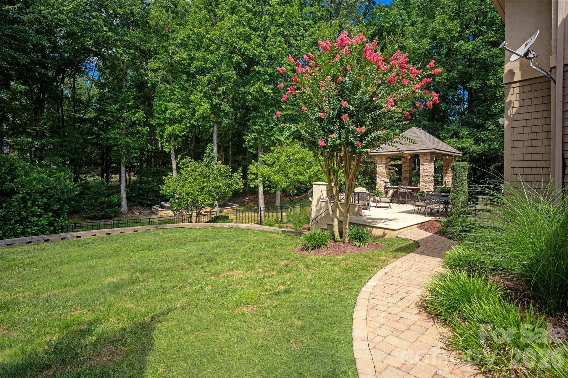 In addition to the grassy area, there is a rear fire pit area beyond the gate that is enclosed with a stone stack low wall and includes a pea gravel base and room for an abundance of seating.