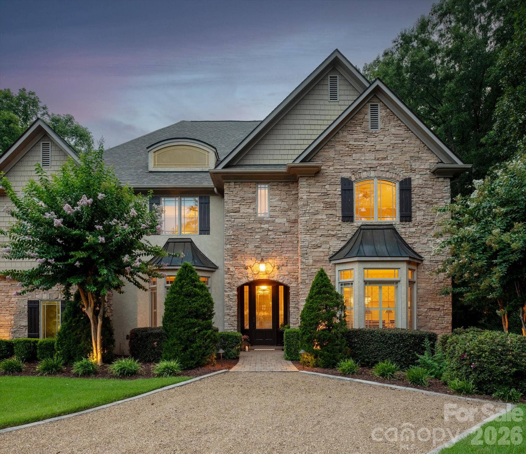 An impressive street presence defined by a pea gravel drive, mature landscaping, a deep setback, and a sprawling, manicured lawn.