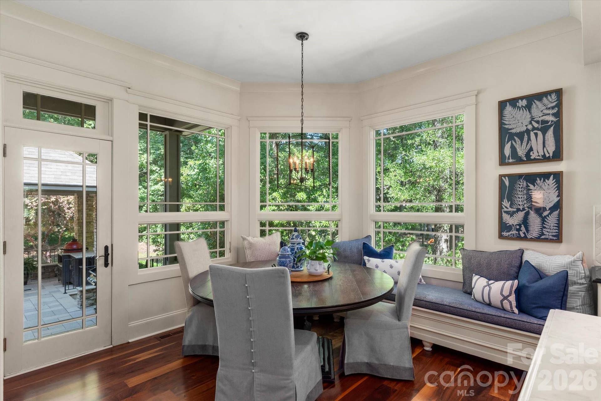 A sun-lit breakfast nook featuring a custom built-in bench with panoramic views of the lush rear grounds.