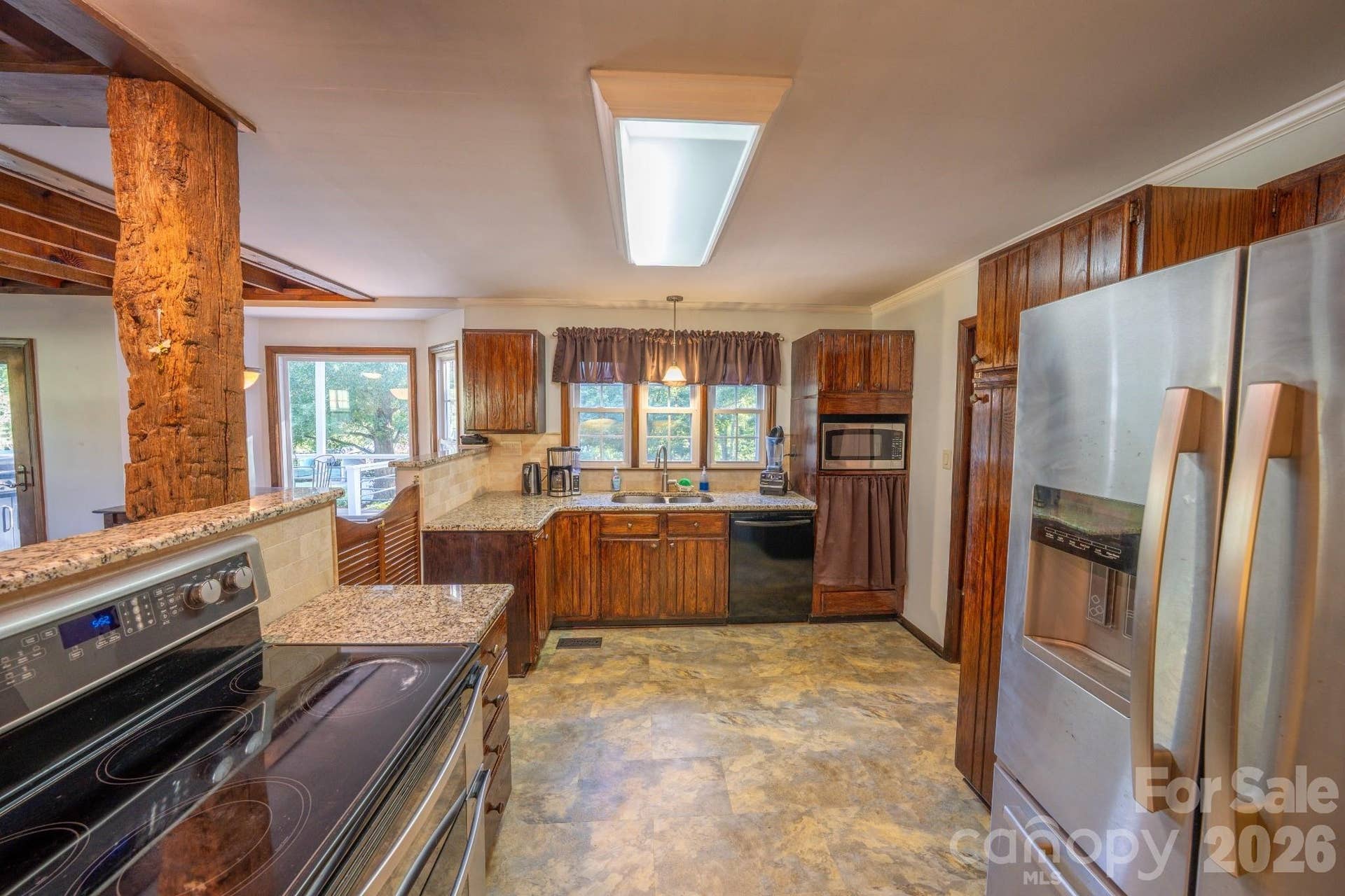Saloon door entry into kitchen w/ Granite countertops, tile backsplash, & pantry closet