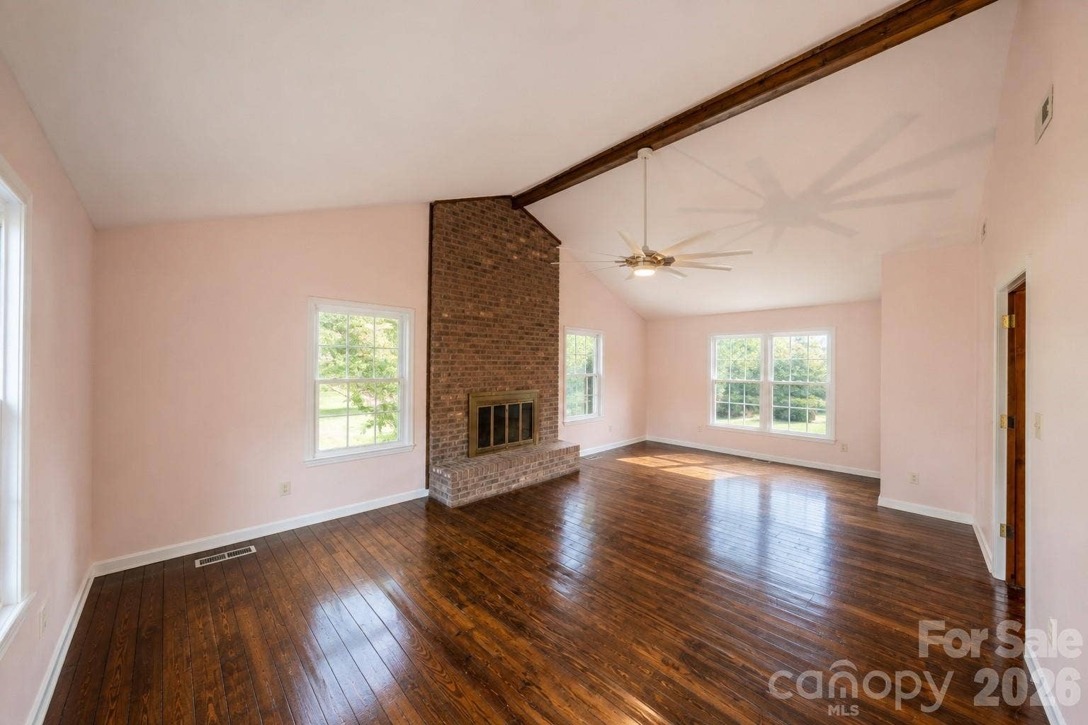 Second floor bedroom with brick surround fire place, ceiling fan, and sitting area