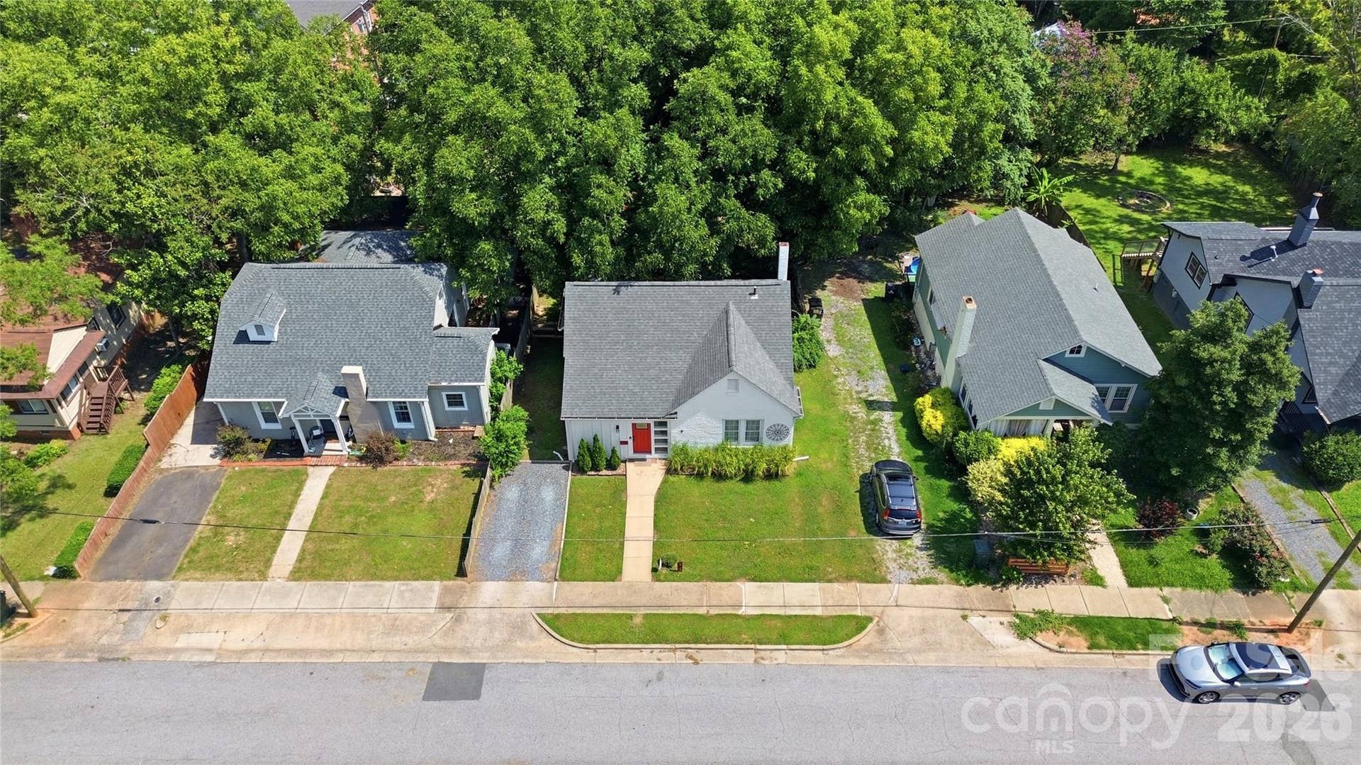 An aerial view highlights the home's mature trees, gravel parking pad, and generous 0.2-acre lot in the heart of Old Town Rock Hill.