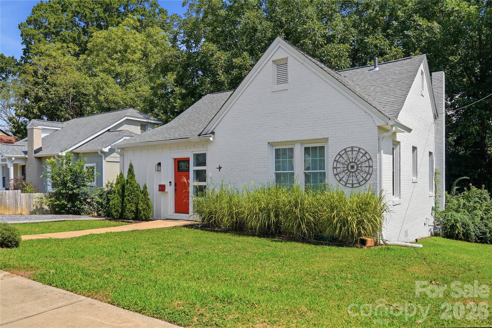 A bold red front door and mature landscaping give this home a fresh, welcoming exterior.