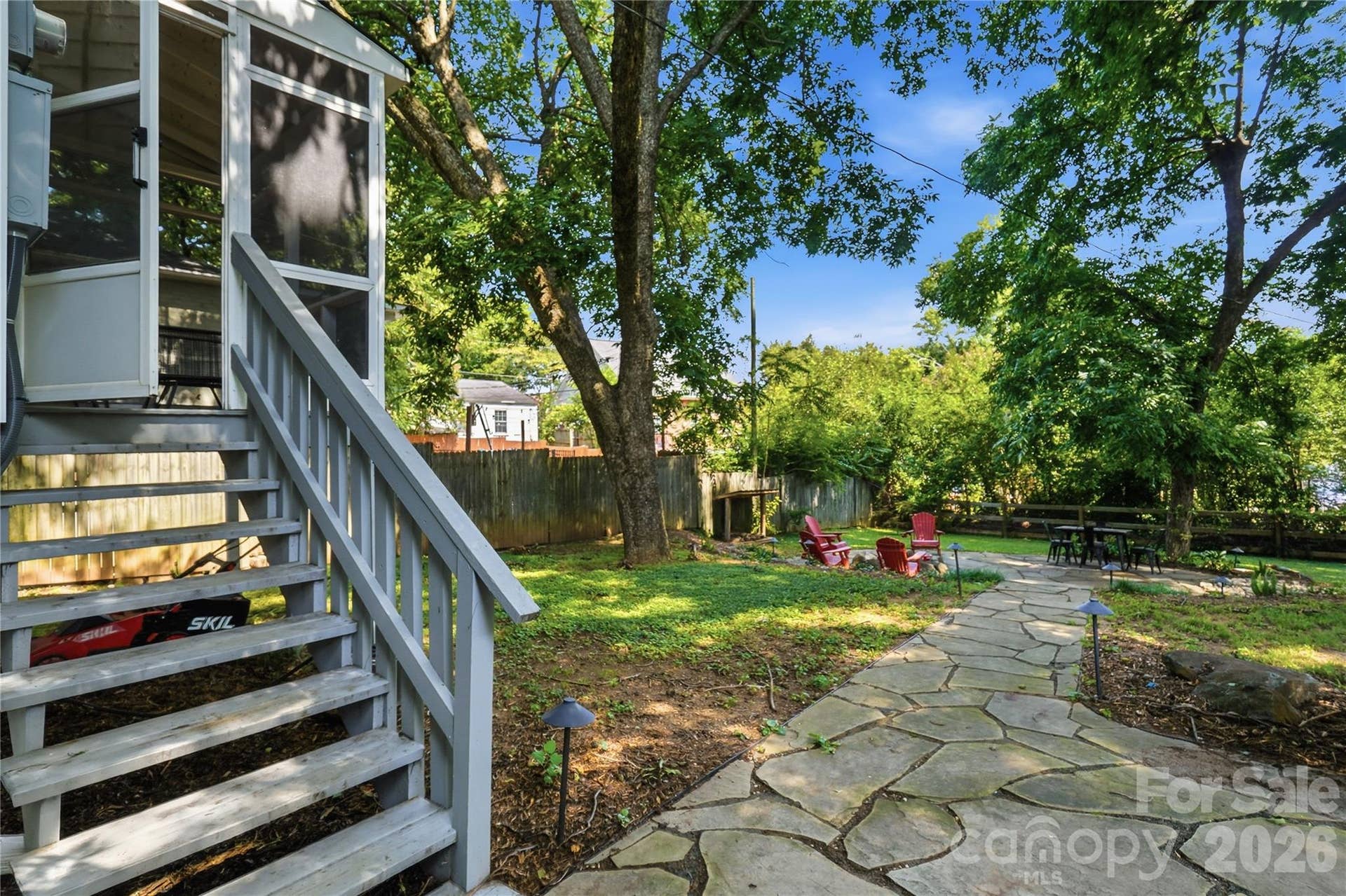 Stairs lead from the screened porch down to the flagstone patio and backyard retreat, with a fire pit area just steps away.