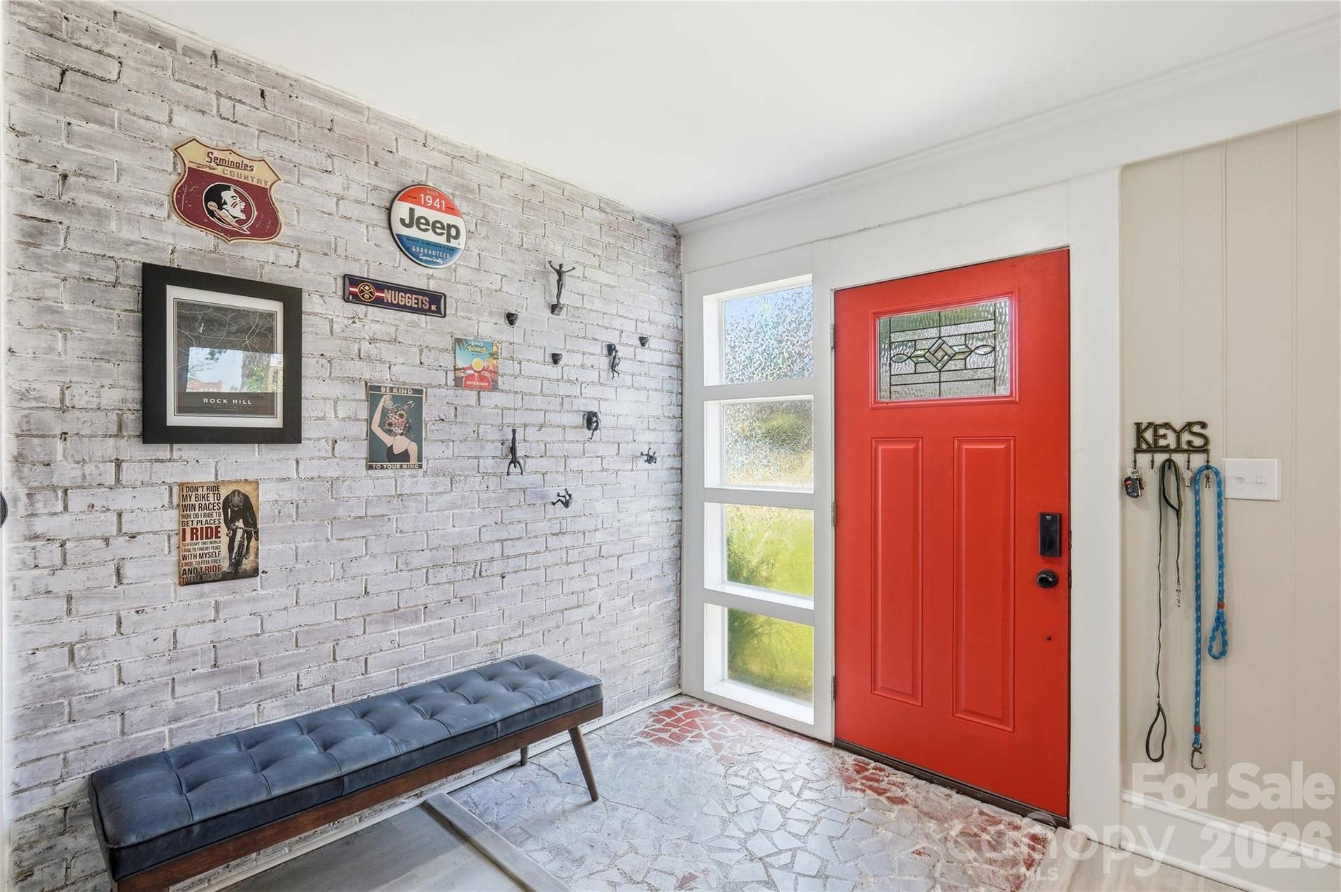 The entryway showcases original whitewashed brick, with a sidelight window beside the front door bringing in extra natural light.