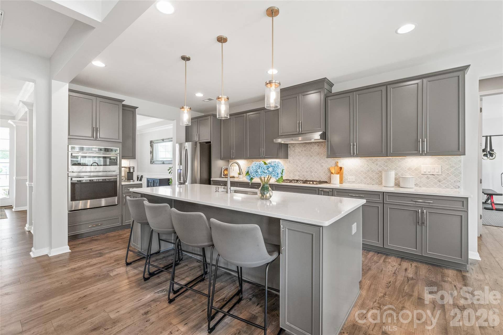 At the heart of the home, this gourmet chefs kitchen shines with an oversized center island, soft-close cabinetry, sleek quartz countertops, stainless steel appliances, and a spacious walk-in pantry.