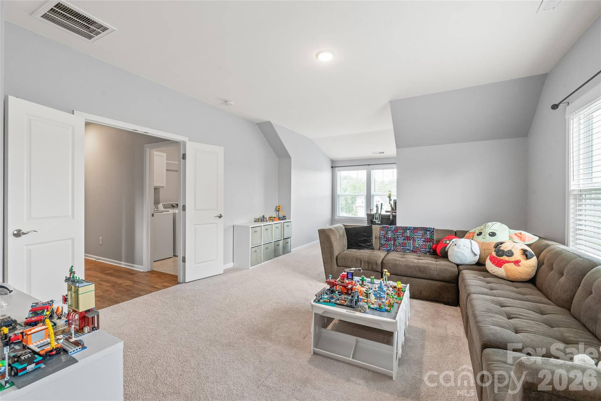 Framed by double doors, this spacious bonus room offers a versatile space perfect for a home theater, play area, or lounge.