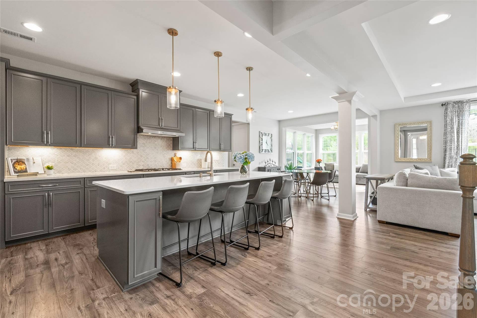Illuminated by ambient under-cabinet lighting, crisp recessed lights, and beautiful statement pendants over the island, this kitchen glows with effortless warmth and style.