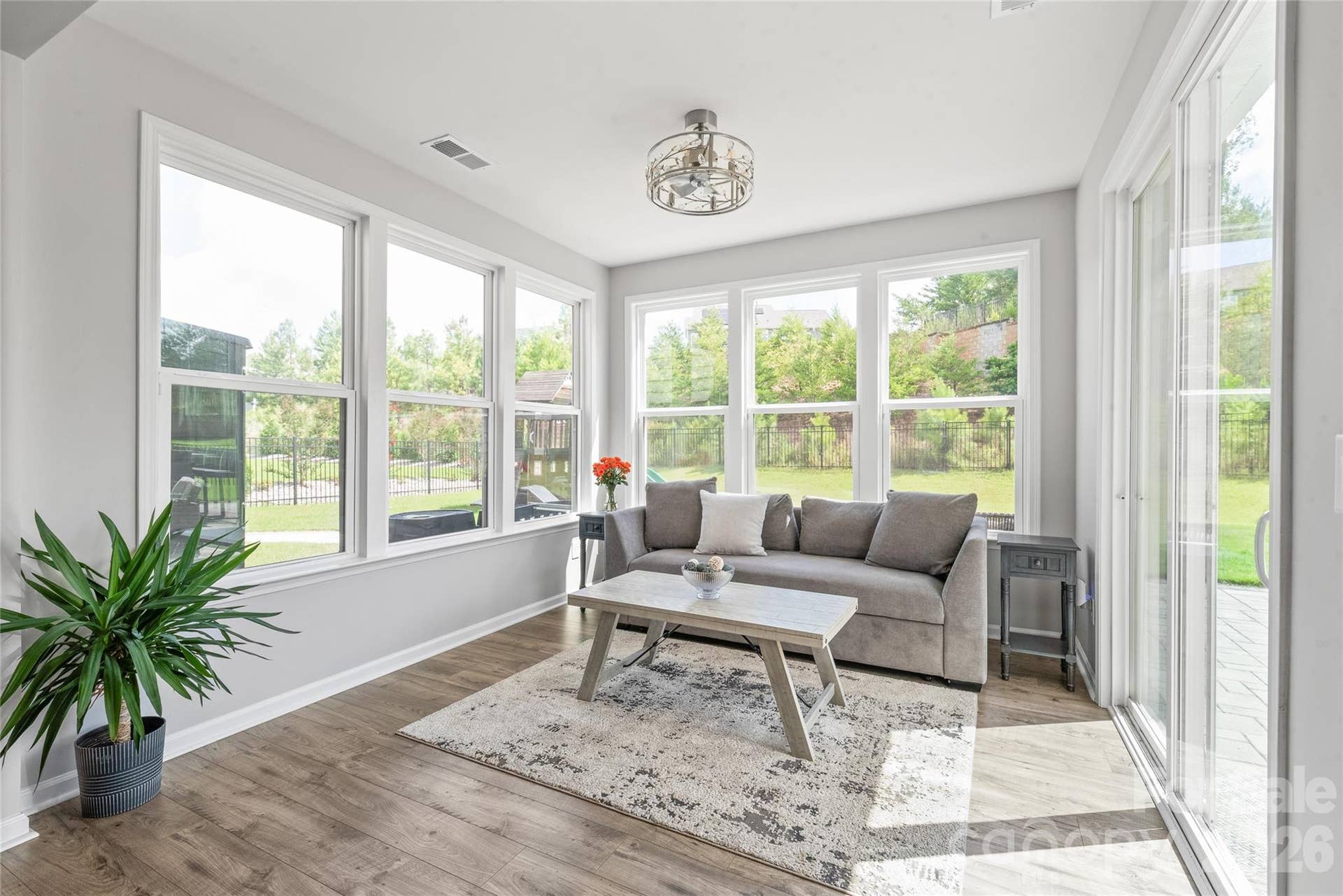 Framed by walls of windows and a sliding glass door, the light-filled sunroom effortlessly blends indoor comfort with seamless access to the outdoor living space.