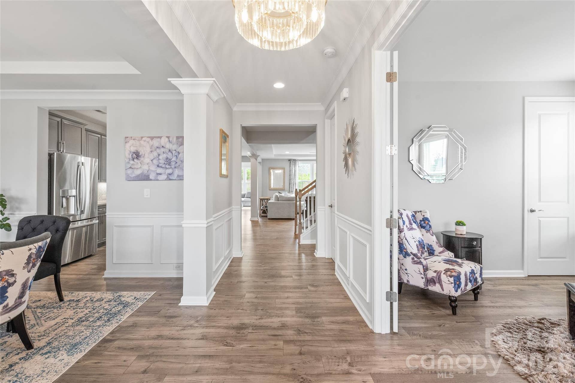 Step into a light-filled entry featuring cohesive LVP flooring, elegant custom trimwork, and updated designer lighting that immediately sets a sophisticated, modern tone.