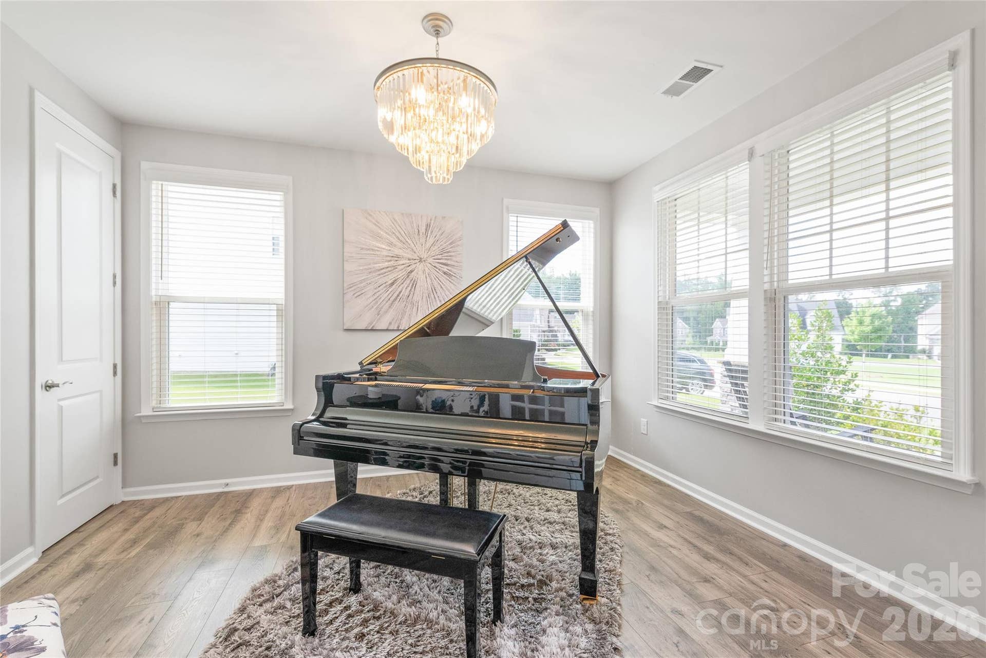Located right off the entry, this versatile office or flex space is bathed in natural light, featuring rich LVP floors and a statement designer chandelier.