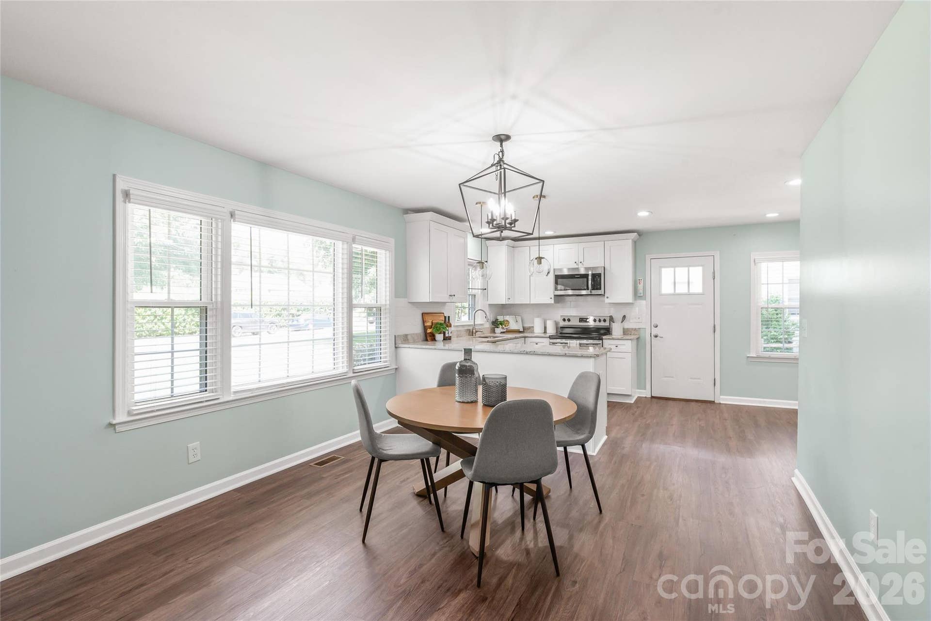 Dining area features custom designer light fixture, seamlessly blending the open living space.
