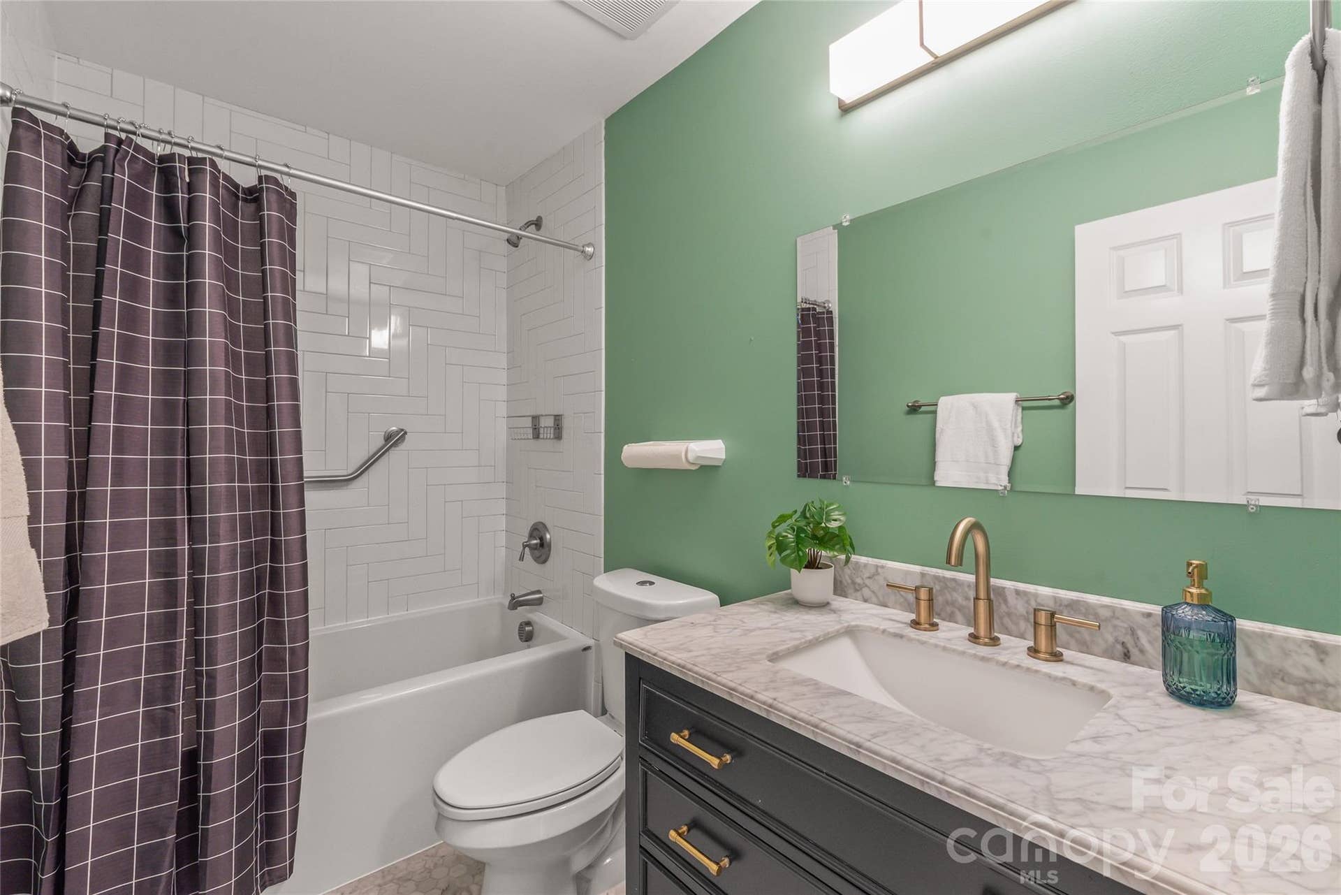 An updated second full bathroom showcasing a classic tub/shower combo enhanced with custom tile extending all the way to the ceiling for a clean, modern look.