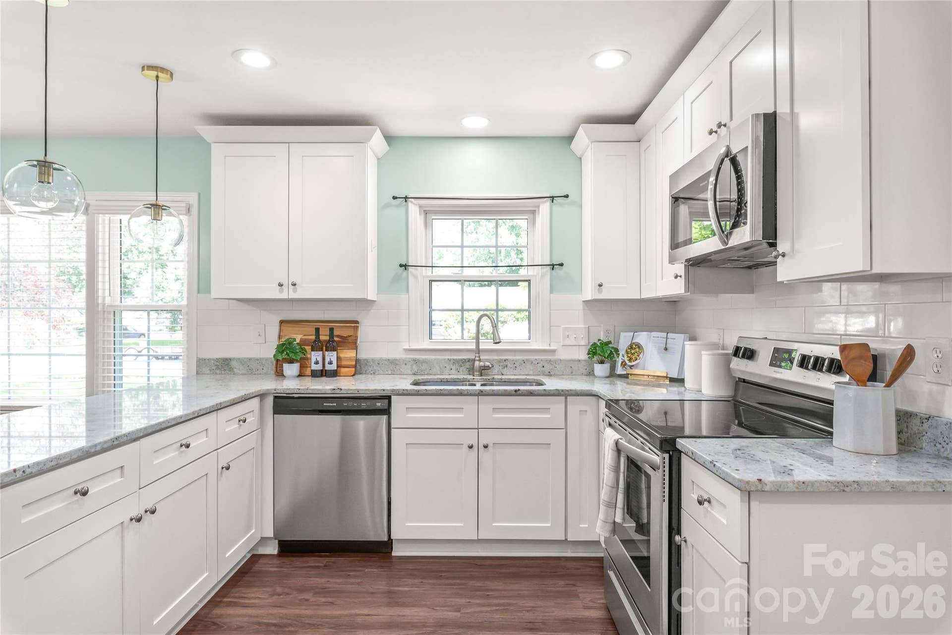 Outfitted with quartz countertops, timeless tile backsplash, and stylish designer pendant lighting that perfectly complements the white shaker cabinetry.