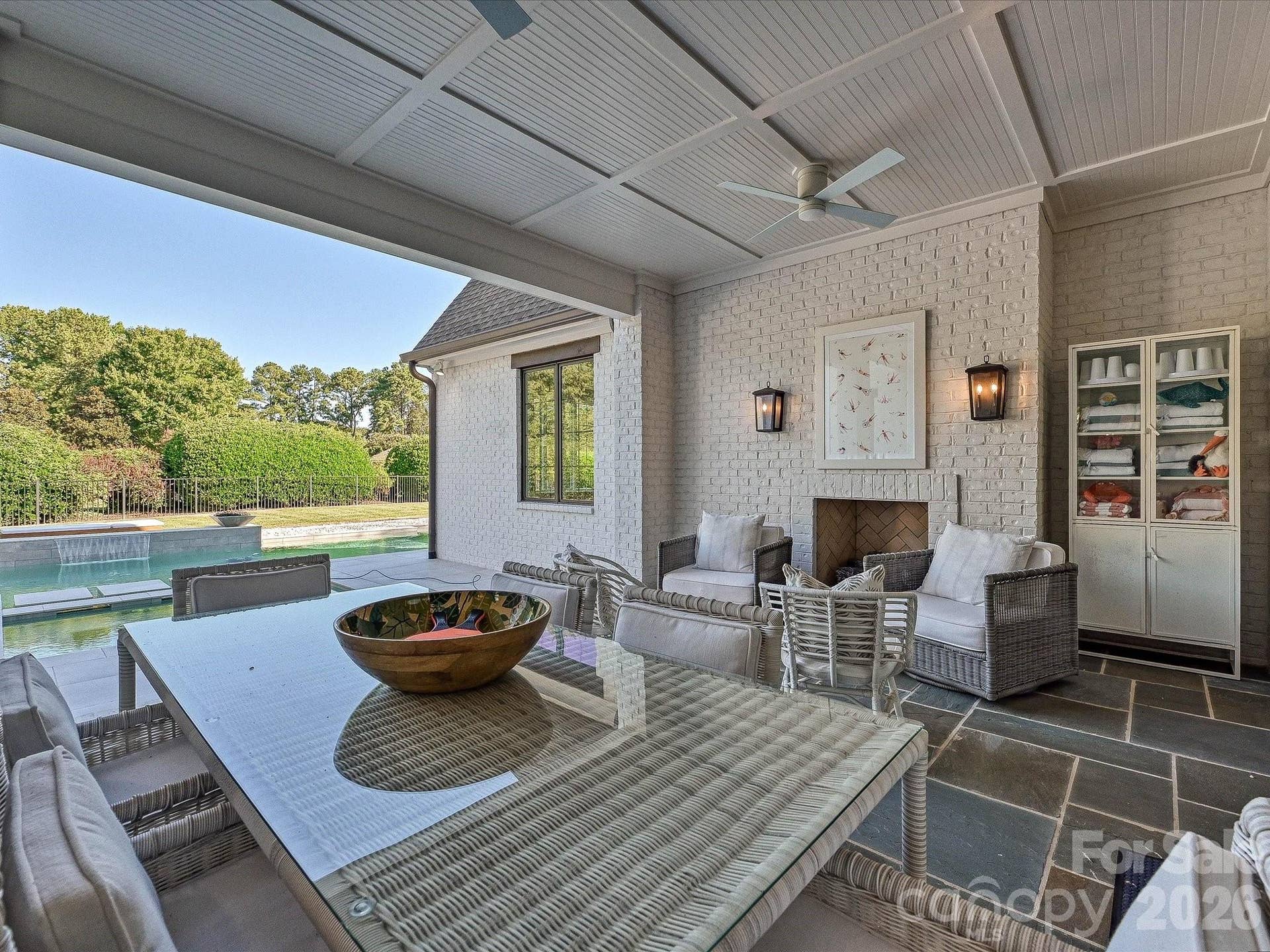 Expansive covered back patio extends the living space outdoors with a fireplace, ceiling fans, dining and lounge areas, and seamless access to the private pool.