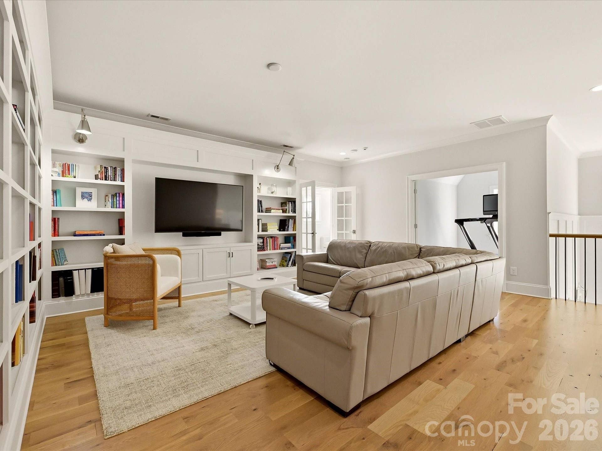 Spacious upper-level loft offers built-in shelving, abundant natural light, and flexible space ideal for a media room, lounge, or casual gathering area.