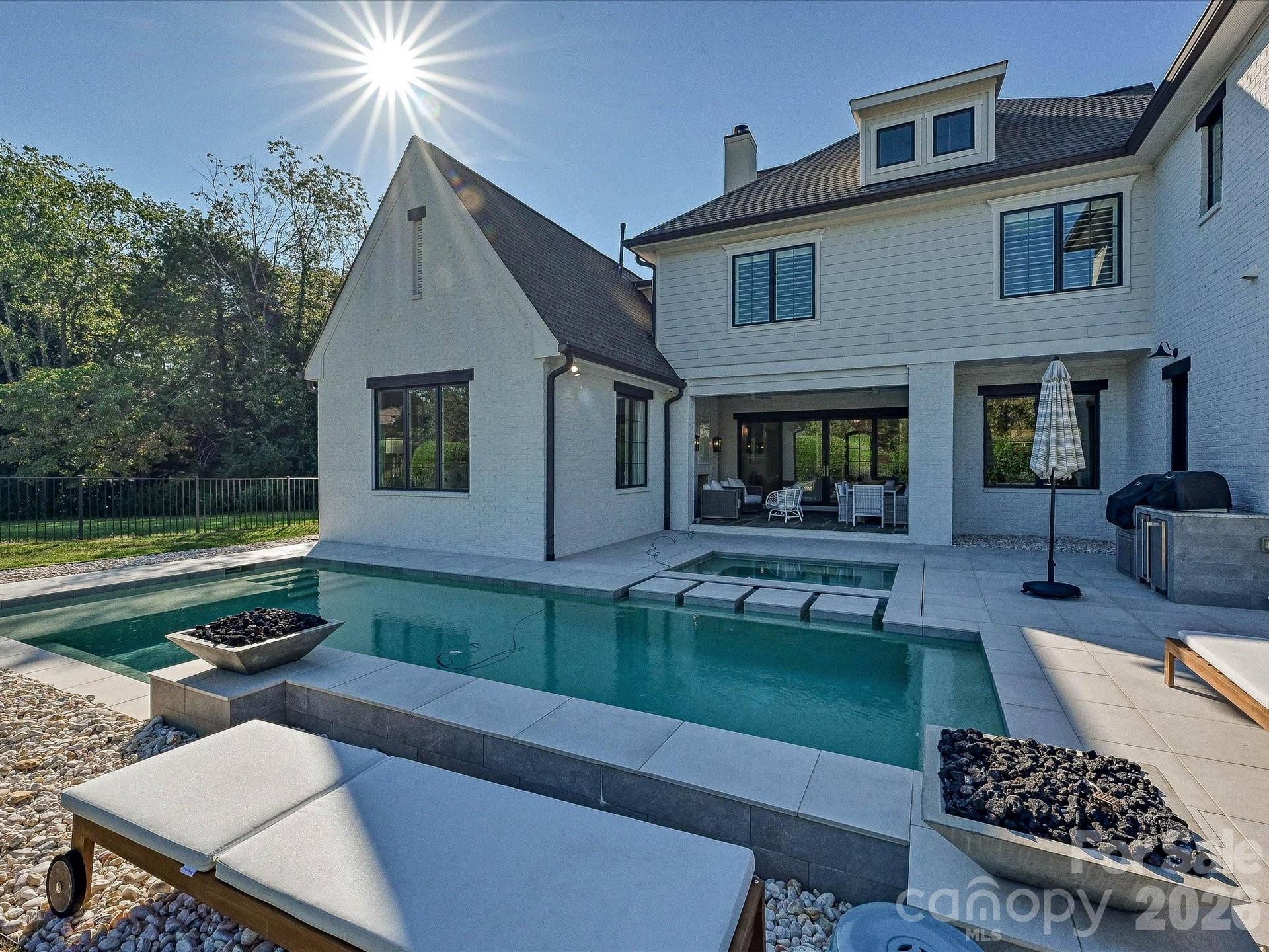 Resort-style backyard showcases a sleek, salt water, heated pool and spa with waterfall feature, expansive patio space, and a private setting ideal for outdoor entertaining and relaxation.