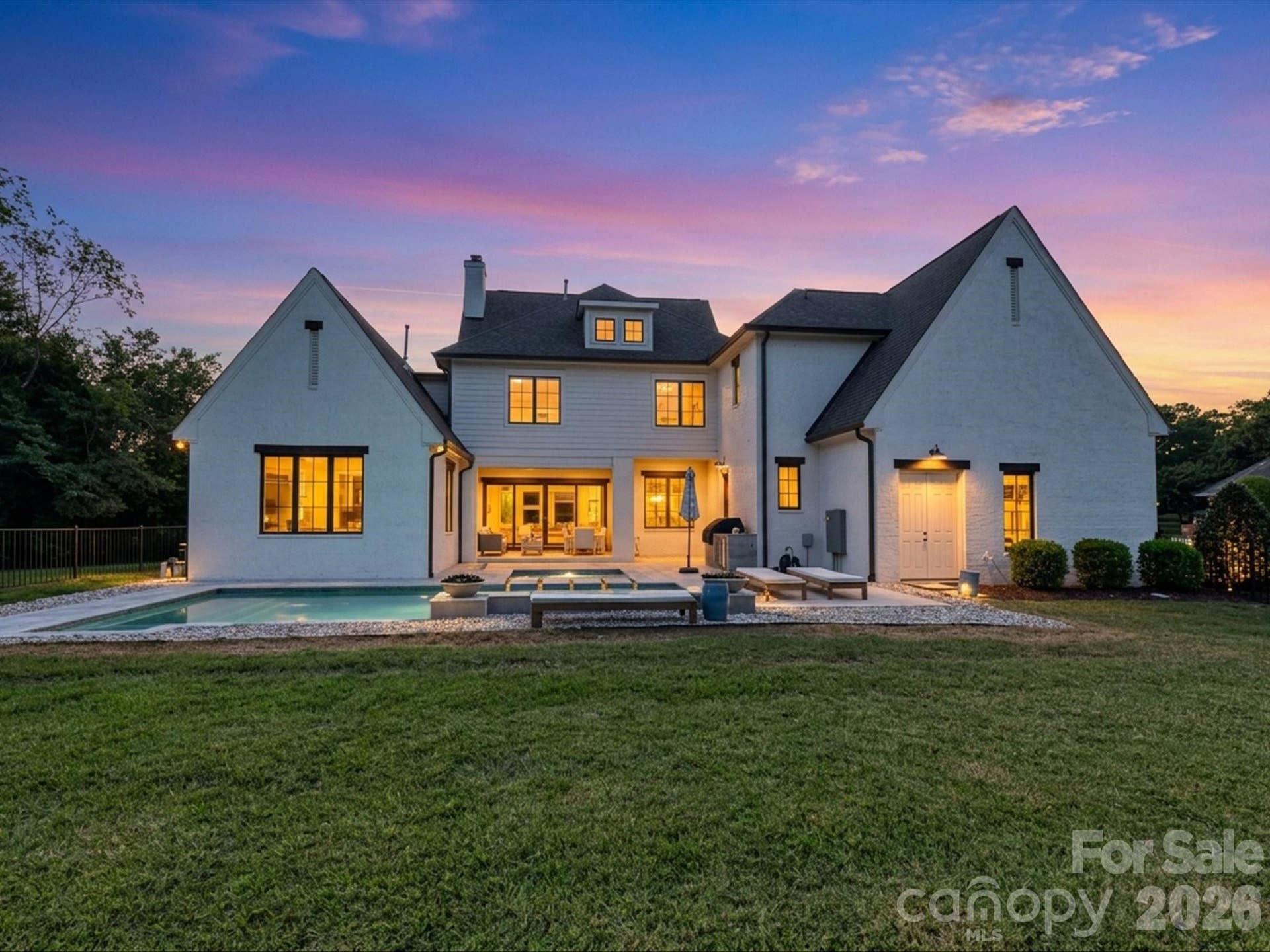 Resort-style outdoor living takes center stage with a sparkling private pool, integrated spa, fire features, and covered patio designed for relaxing or entertaining after sunset.