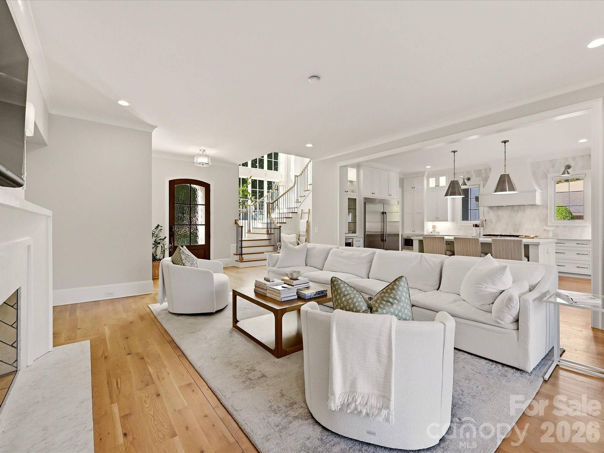 Light-filled Great Room features warm hardwood floors, a sleek fireplace with built-ins, seamless flow to the kitchen, and expansive glass doors opening to the covered outdoor living area.