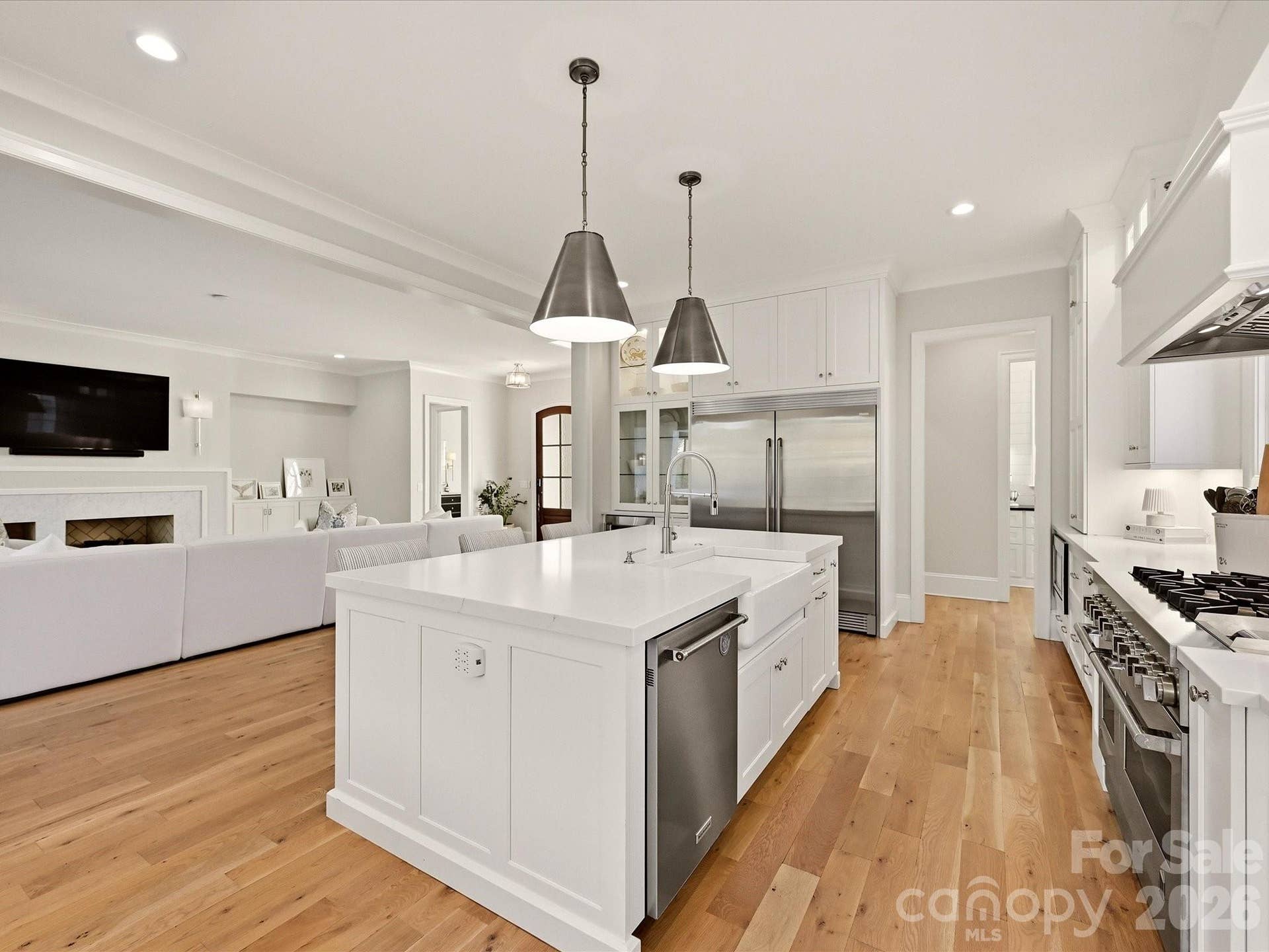 The kitchen flows effortlessly into a sunlit breakfast area, where expansive windows, hardwood floors, and views toward the covered patio create an inviting setting for casual dining.