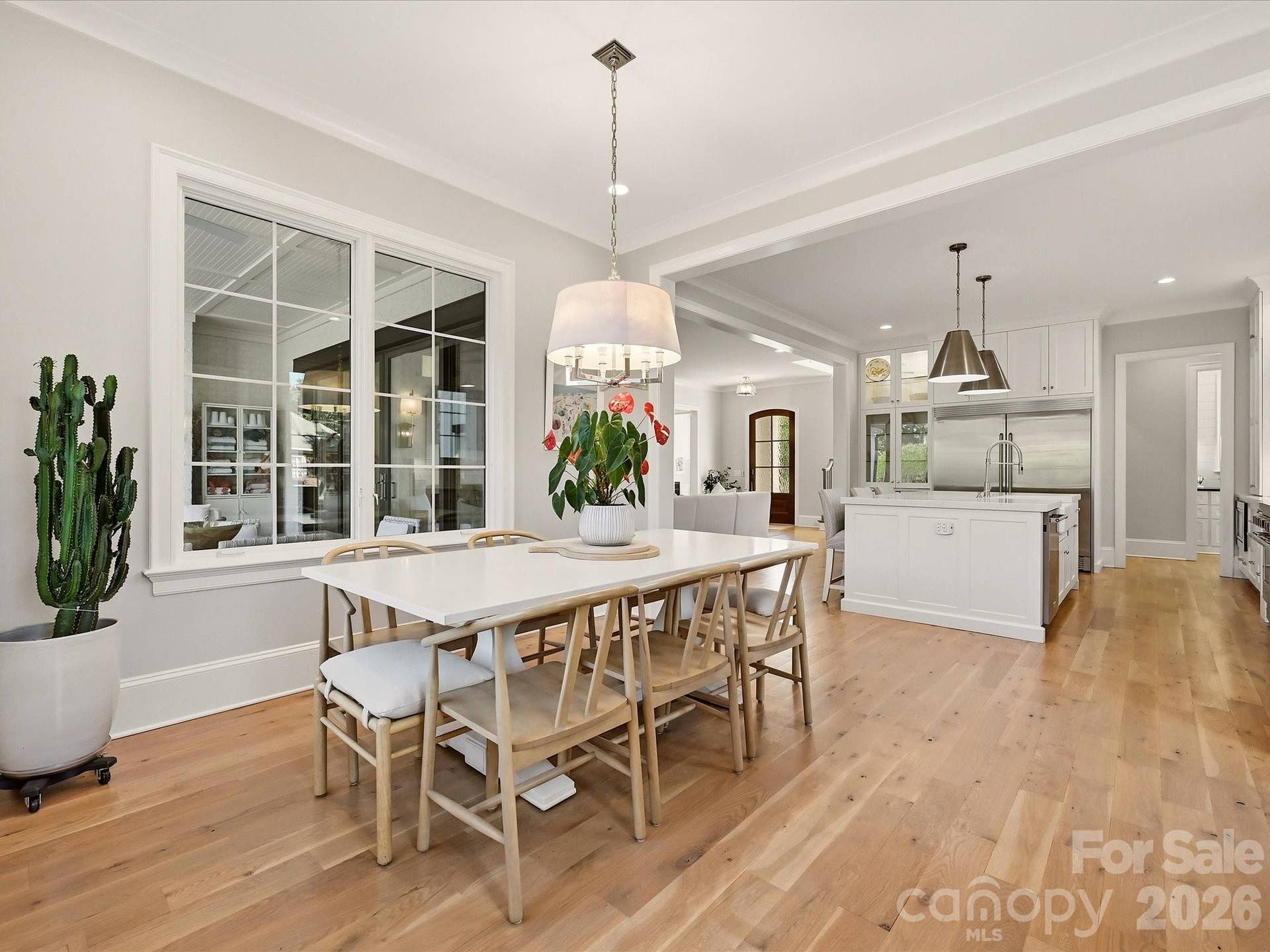 The kitchen flows effortlessly into a sunlit breakfast area, where expansive windows, hardwood floors, and views toward the covered patio create an inviting setting for casual dining.