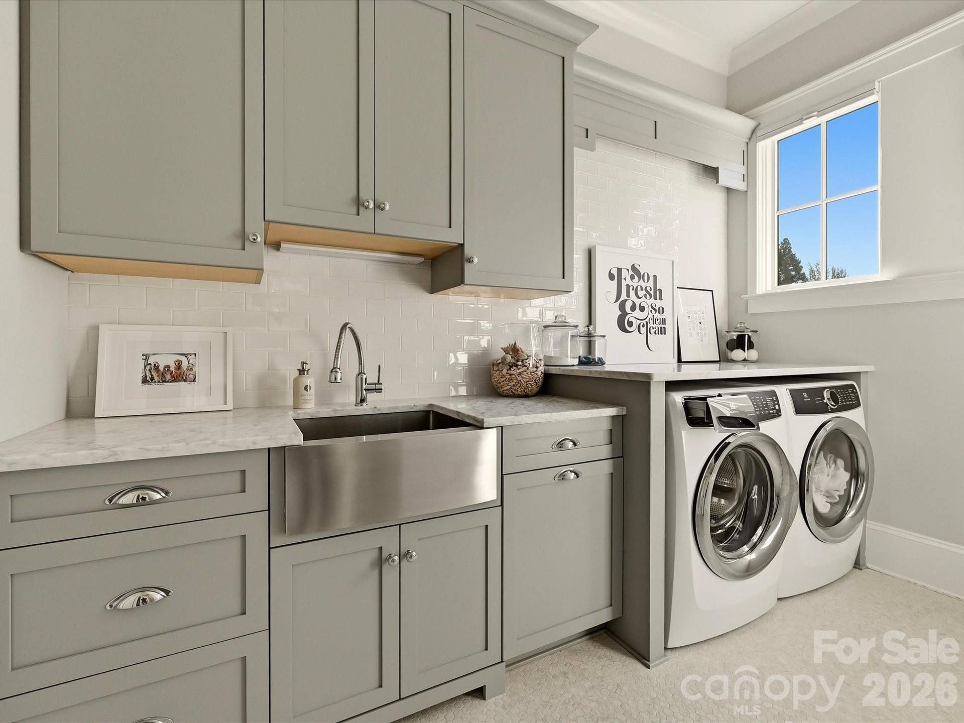 Well-appointed laundry room features custom cabinetry, generous counter space, a utility sink, and convenient built-in storage for added everyday functionality.