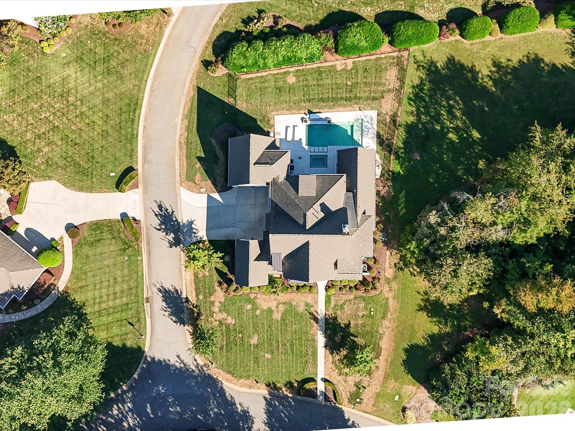 Aerial view highlights the homes spacious homesite, private pool, and beautifully landscaped setting within the surrounding neighborhood.