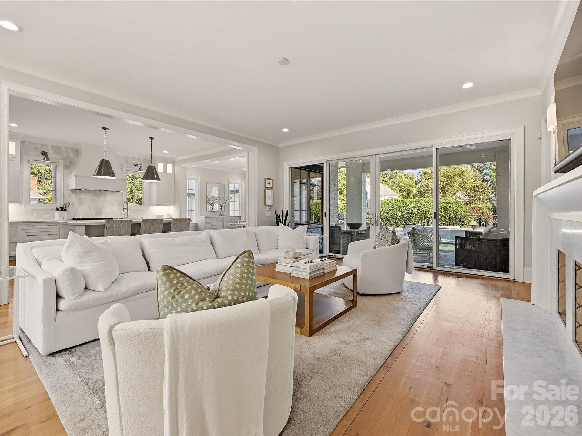 Light-filled Great Room features warm hardwood floors, a sleek fireplace with built-ins, seamless flow to the kitchen, and expansive glass doors opening to the covered outdoor living area.