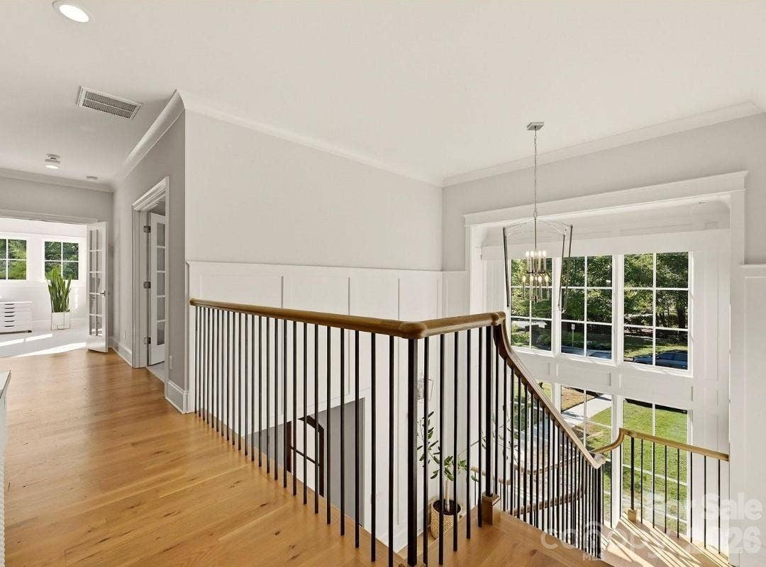 Bright upper-level landing overlooks the dramatic two-story foyer and showcases hardwood floors, custom millwork, and an open staircase filled with natural light.