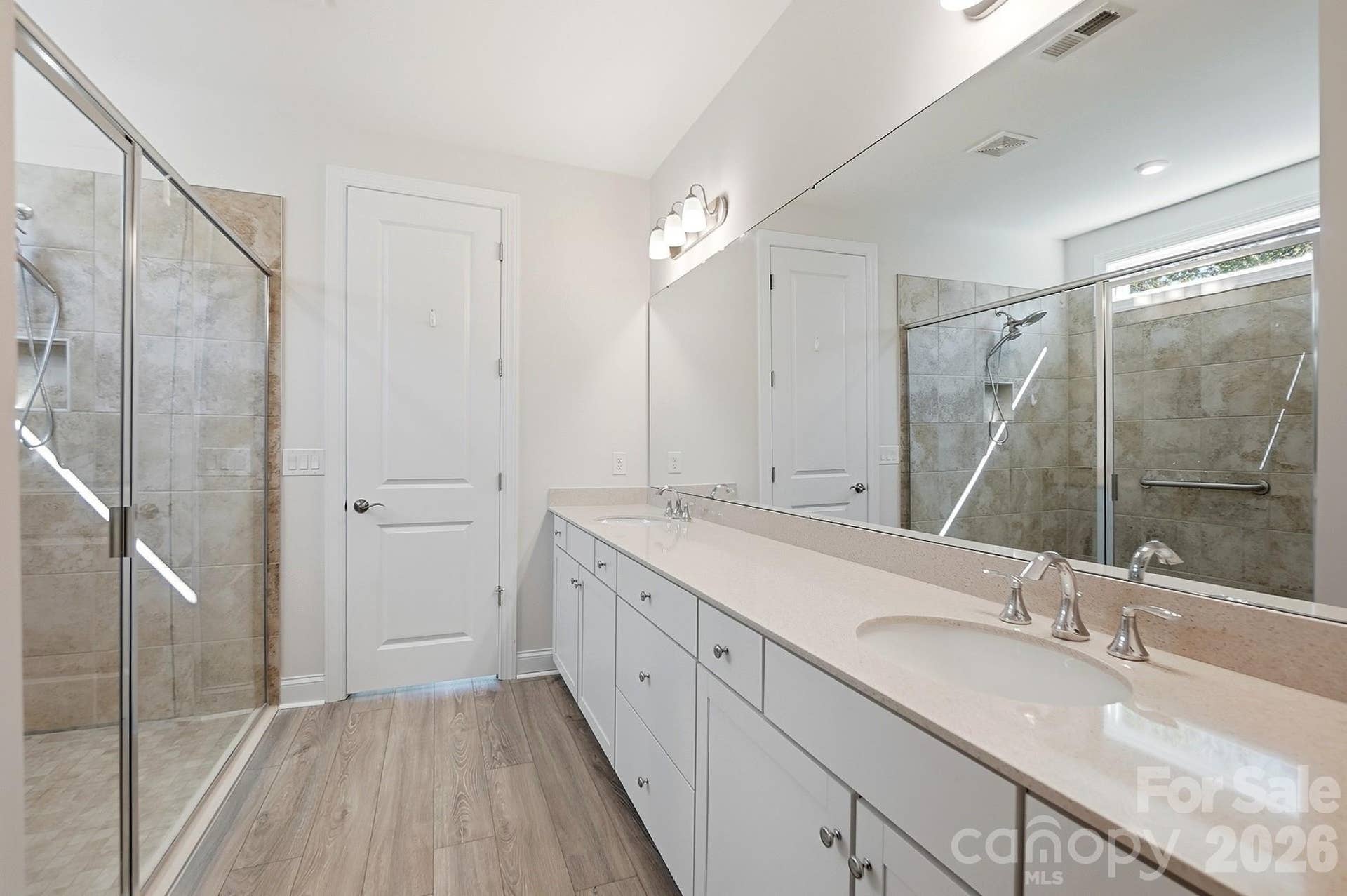 8032 Longwaters Court, York, SC 29745 Luxurious primary bath offers dual vanities, an oversized walk-in tile shower with handicap grab bar, and a large walk-in closet