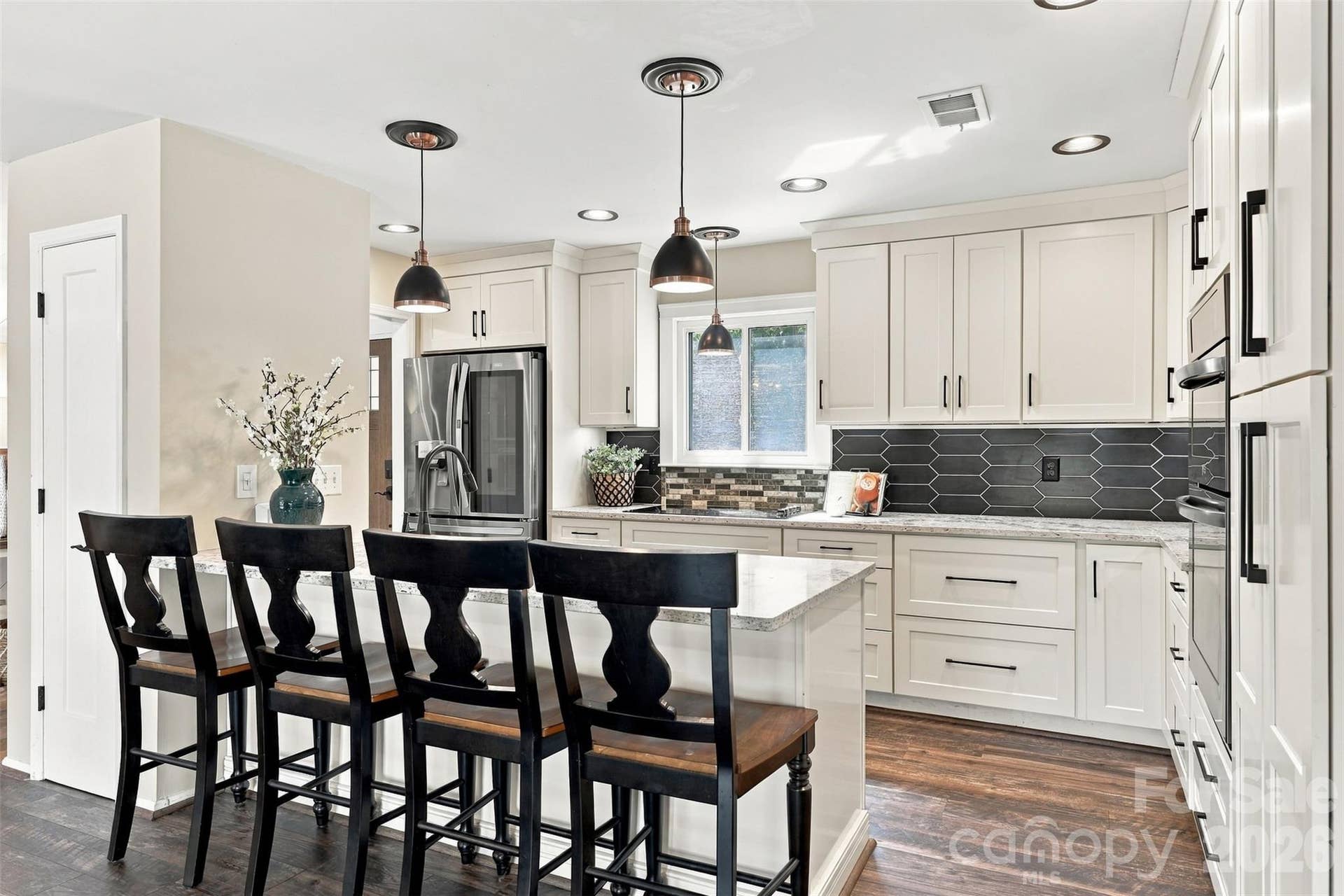 Updated kitchen with breakfast bar, granite countertops, custom cabinetry, stainless steel appliances, tile backsplash and pantry