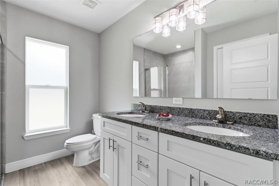 Primary bathroom has double sinks, taller white wood vanity and granite countertop