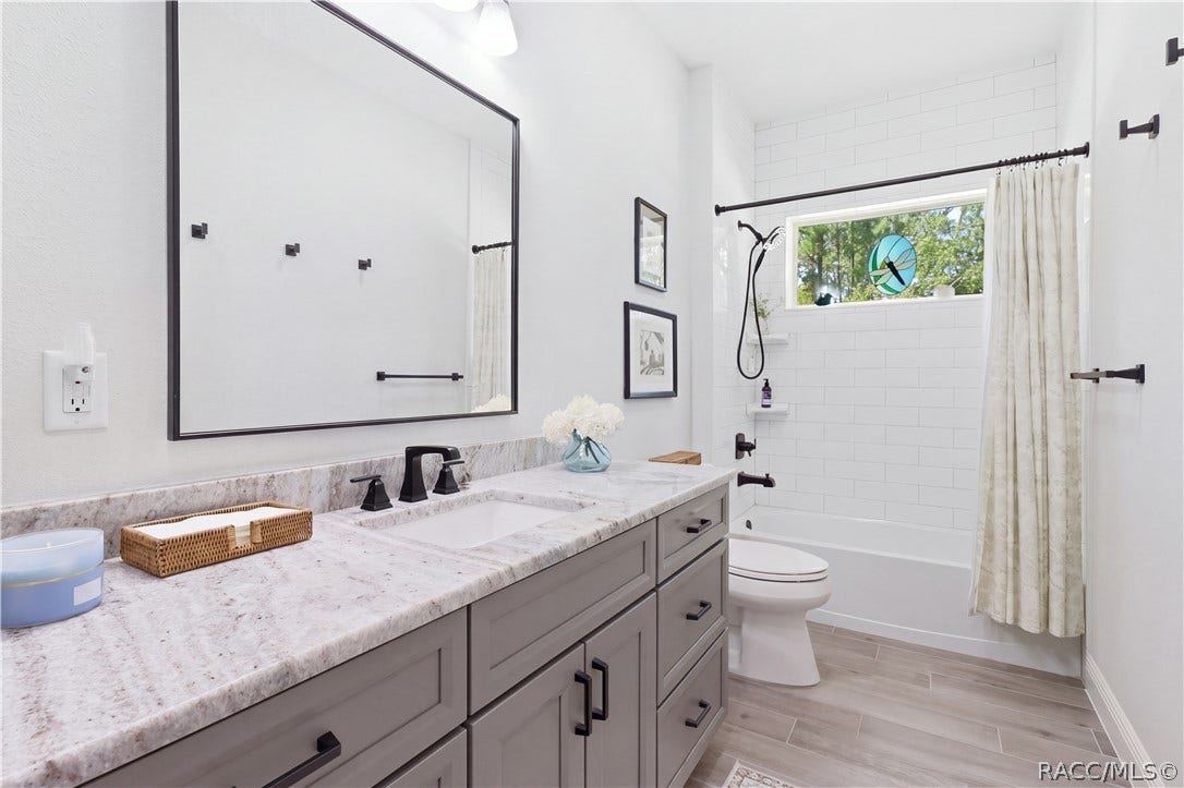 4124 W Pine Ridge Boulevard, Beverly Hills, FL 34465 GUEST BATHROOM Stylish guest bath features a large vanity w/ abundant storage, granite countertop, oversized framed mirror & matte-black fixtures. The tub/tiled shower is surrounded by classic white tile & accented by a horizontal window bringing in natural light.