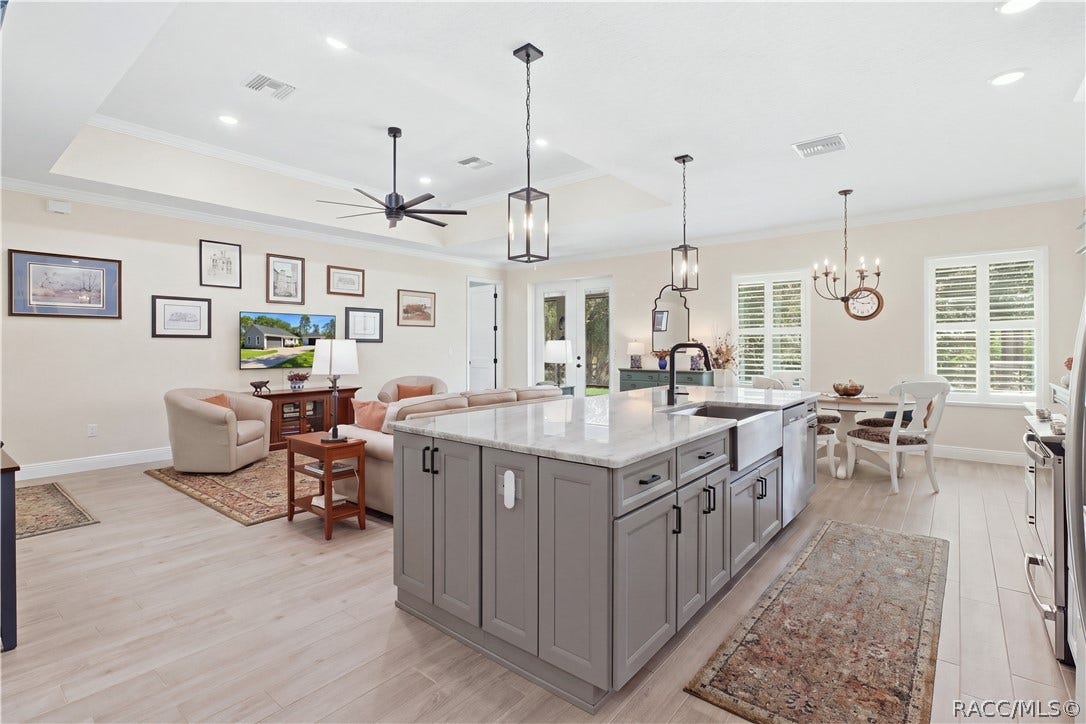 4124 W Pine Ridge Boulevard, Beverly Hills, FL 34465 KITCHEN + GREAT ROOM Oversized contrasting island anchors the open floor plan w/ expansive stone-look counters, farmhouse-style stainless sink, statement faucet, pendant lighting & abundant cabinetry.