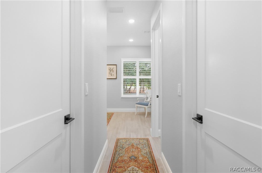 4124 W Pine Ridge Boulevard, Beverly Hills, FL 34465 PRIVATE PRIMARY SUITE HALLWAY Clean, thoughtfully designed hallway connects the primary bedroom to the ensuite bath, featuring recessed lighting, porcelain tile flooring, crisp white trim & contemporary black door hardware.