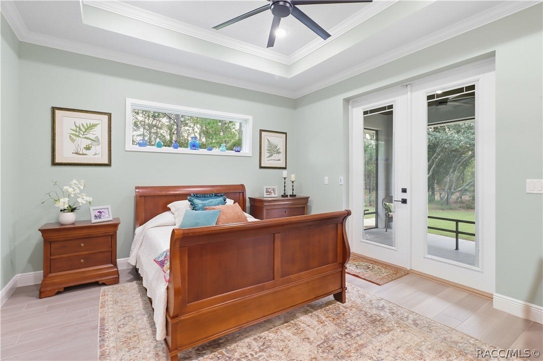 4124 W Pine Ridge Boulevard, Beverly Hills, FL 34465 BEDROOM RETREAT Spacious bedroom features a tray ceiling w/ crown molding, modern ceiling fan, high horizontal accent window, light flooring & glass doors opening to a covered screened outdoor area.