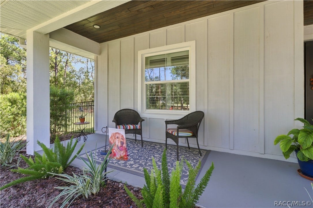 4124 W Pine Ridge Boulevard, Beverly Hills, FL 34465 COVERED FRONT PORCH A cozy sitting area under the covered porch features a rich wood plank ceiling, recessed lighting, landscaped greenery & views across the property.