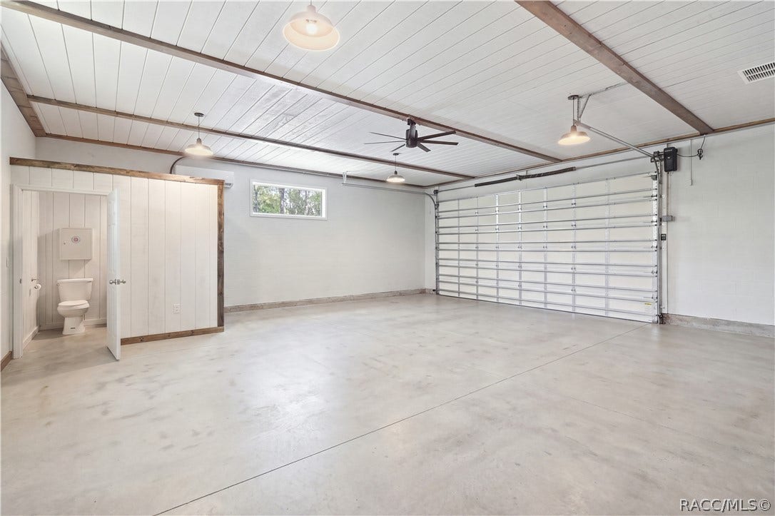 4124 W Pine Ridge Boulevard, Beverly Hills, FL 34465 OVERSIZED DETACHED 30x30 GARAGE THIS IS THE BONUS!
The detached garage delivers serious versatility w/ an expansive open interior, high plank-style ceiling, exposed wood beam accents, multiple pendant lights & a large modern ceiling fan. A full-size garage door provides easy vehicle access, while a separate enclosed area adds even more functionality w/ its own private bathroom.
