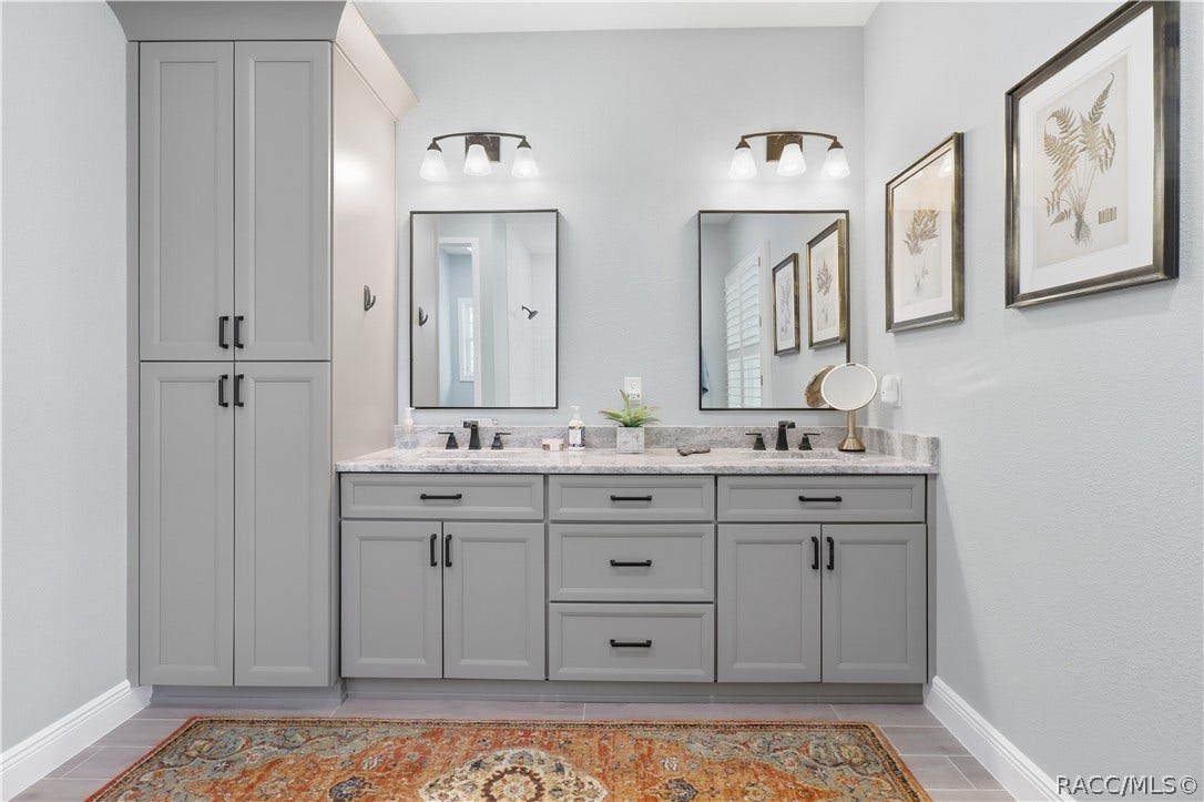 4124 W Pine Ridge Boulevard, Beverly Hills, FL 34465 PRIMARY BATH DUAL VANITY Beautifully finished primary bath features an expansive dual-sink vanity w/
abundant cabinetry, granite countertops, individual framed mirrors & stylish black fixtures. A full-height
linen/storage cabinet adds exceptional everyday storage.