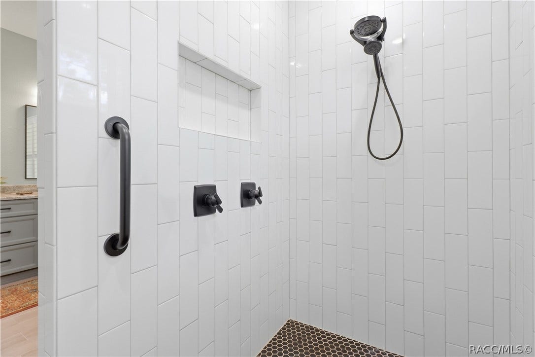 4124 W Pine Ridge Boulevard, Beverly Hills, FL 34465 WALK-IN TILED SHOWER Gorgeous walk-in shower is finished from floor to ceiling in crisp white tile w/ contrasting dark hexagon tile flooring, built-in recessed niche, grab bar & handheld showerhead. Matte-black fixtures give the space a sharp, modern finish.