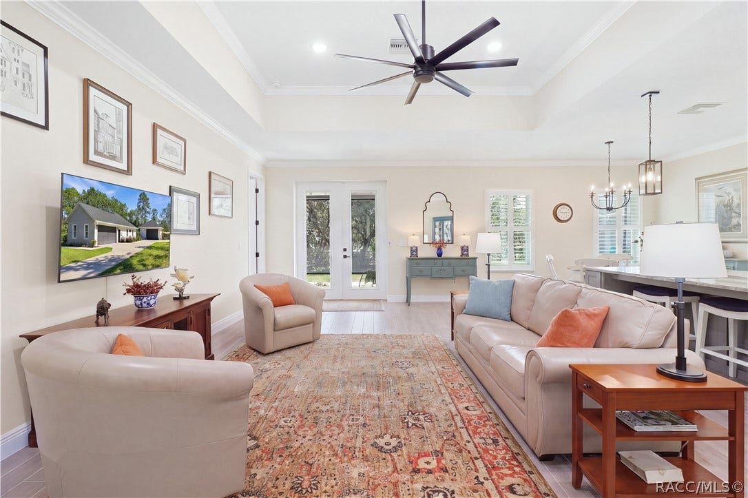 4124 W Pine Ridge Boulevard, Beverly Hills, FL 34465 GREAT ROOM VIEW Airy living space w/ tray ceiling, crown molding, modern ceiling fan, abundant natural light & French-style glass doors opening toward the outdoor living area.
