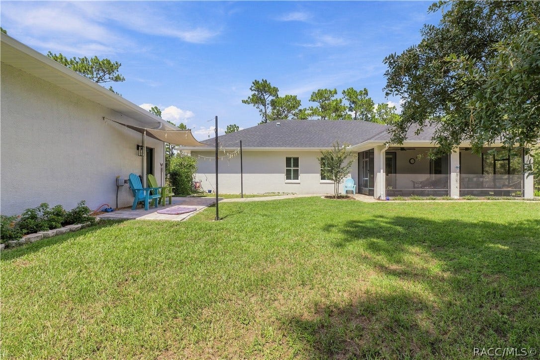 4124 W Pine Ridge Boulevard, Beverly Hills, FL 34465 BACKYARD VIEW Wide backyard view showcases the main home's screened lanai, detached garage/outbuilding & expansive lawn connecting the two. Mature trees surrounding the property add a wonderful sense of privacy while leaving plenty of usable outdoor space.