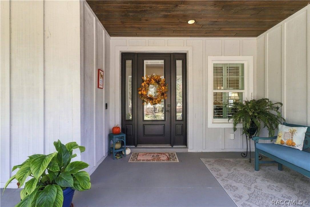 4124 W Pine Ridge Boulevard, Beverly Hills, FL 34465 FRONT DOOR DETAIL Striking dark entry door w/ glass panel & sidelights, wood plank porch ceiling, recessed lighting & a comfortable covered seating area.