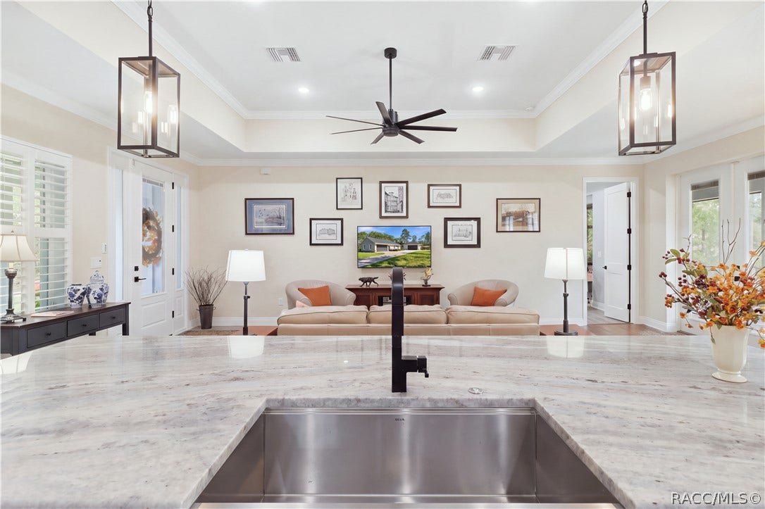 4124 W Pine Ridge Boulevard, Beverly Hills, FL 34465 ISLAND VIEW Looking across the oversized island & deep stainless sink into the great room showcases the home's open sightlines, tray ceiling, pendant lights & spacious gathering areas.