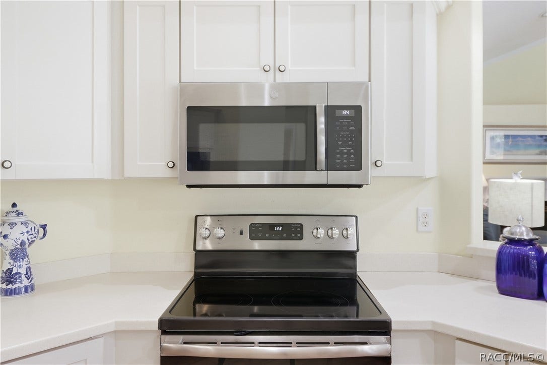 2593 S Columbine Avenue, Homosassa, FL 34448 Kitchen Appliances NEWER Stainless-steel electric range & built-in microwave surrounded by white cabinetry and corian countertops.