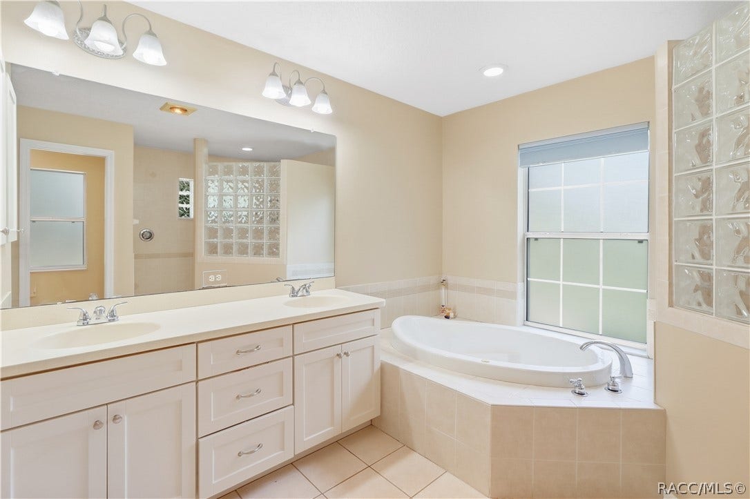 2593 S Columbine Avenue, Homosassa, FL 34448 Primary Bathroom Spacious ensuite featuring a dual-sink vanity, large mirror, soaking jetted tub and tile flooring.