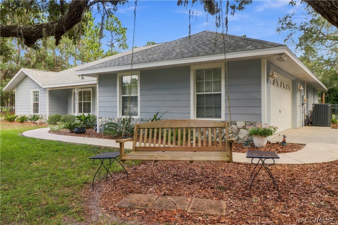 2593 S Columbine Avenue, Homosassa, FL 34448 Front/Side Exterior BRAND NEW ROOF 2026 Side perspective showcasing the home's extended covered front porch, stone accents, mature landscaping. (Swing does not convey).