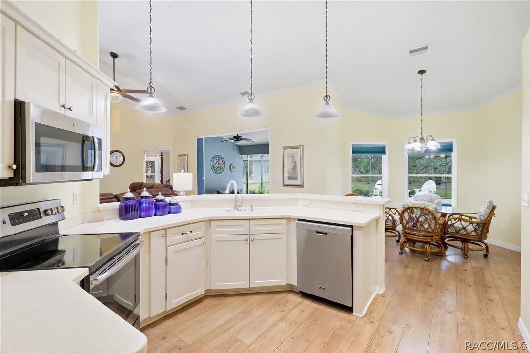 2593 S Columbine Avenue, Homosassa, FL 34448 Kitchen & Kitchen Nook Area Open kitchen featuring abundant cabinetry, corian countertops, breakfast bar, NEWER stainless-steel appliances & adjoining dining area.