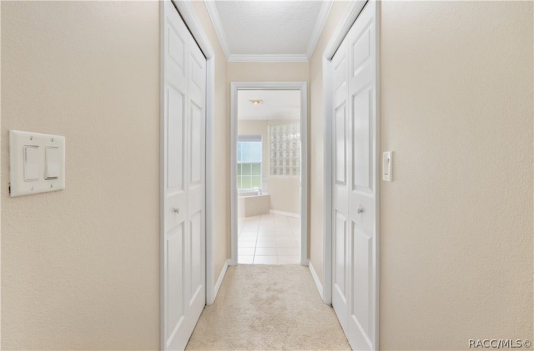2593 S Columbine Avenue, Homosassa, FL 34448 Primary Suite Hallway Hallway leading from the primary bedroom to the ensuite bath, with closets on both sides for added storage.